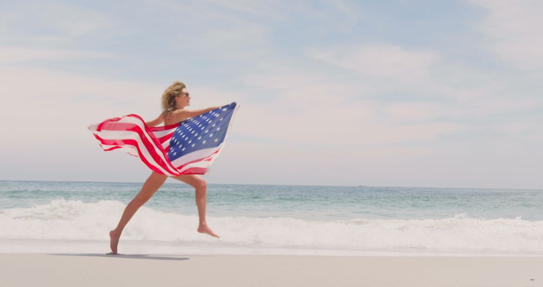 Woman Joyfully Running on Beach with American Flag on Sunny Day