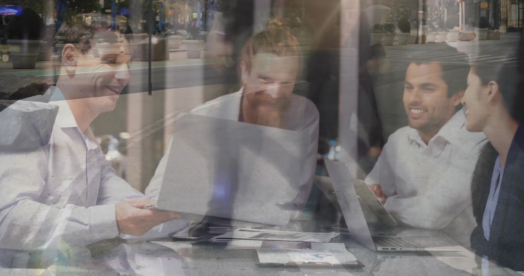 Colleagues Collaborating Through Window Reflection with Laptops and Documents Urban Office