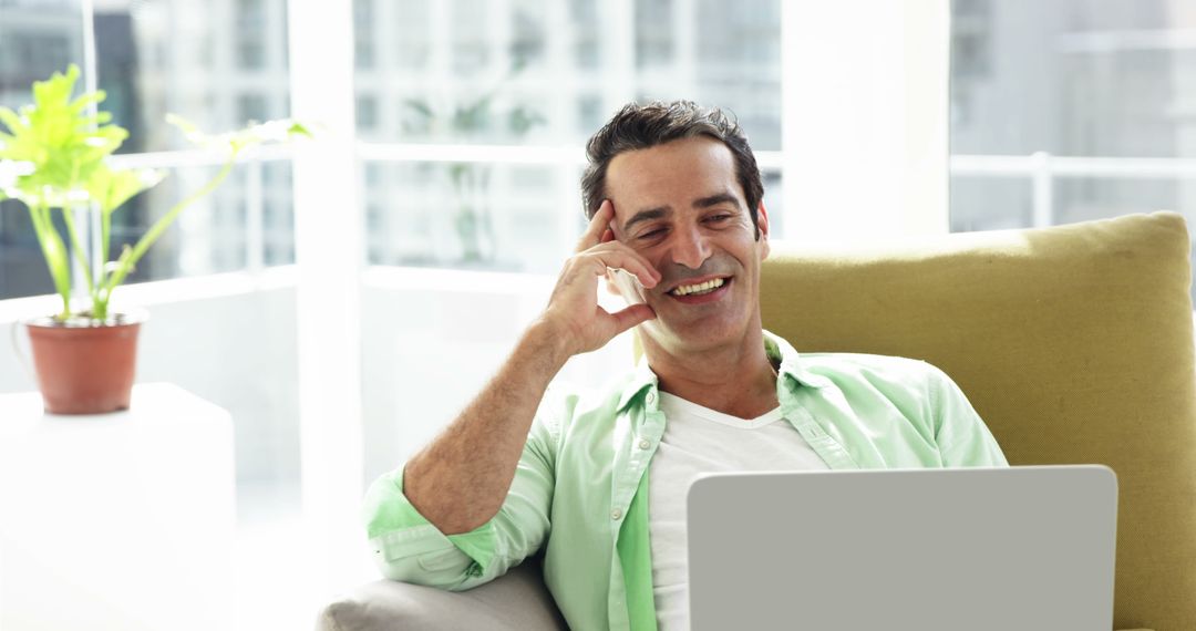 Happy Man Dressed in Light Green Shirt Working on Laptop at Home - Free Images, Stock Photos and Pictures on Pikwizard.com