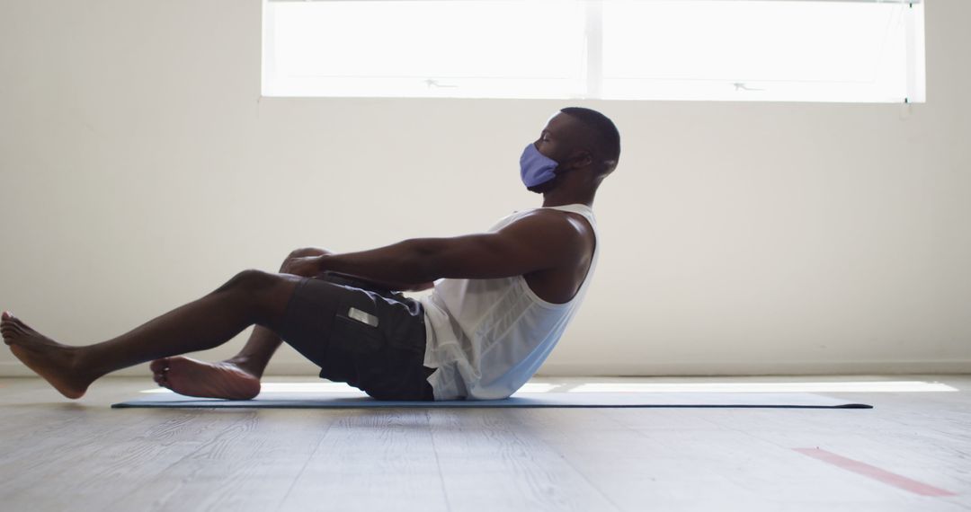 Athletic Man Wearing Mask Performing Crunches on Exercise Mat Indoors - Free Images, Stock Photos and Pictures on Pikwizard.com