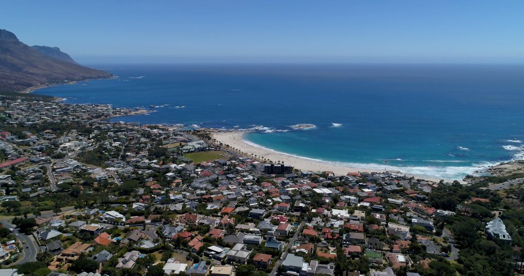 Coastal Cityscape with Ocean and Mountains Under Clear Blue Sky