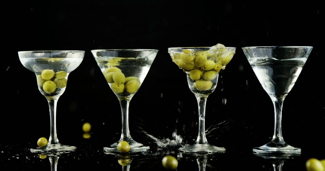 Olives Splashing into Martini Glasses on Black Background