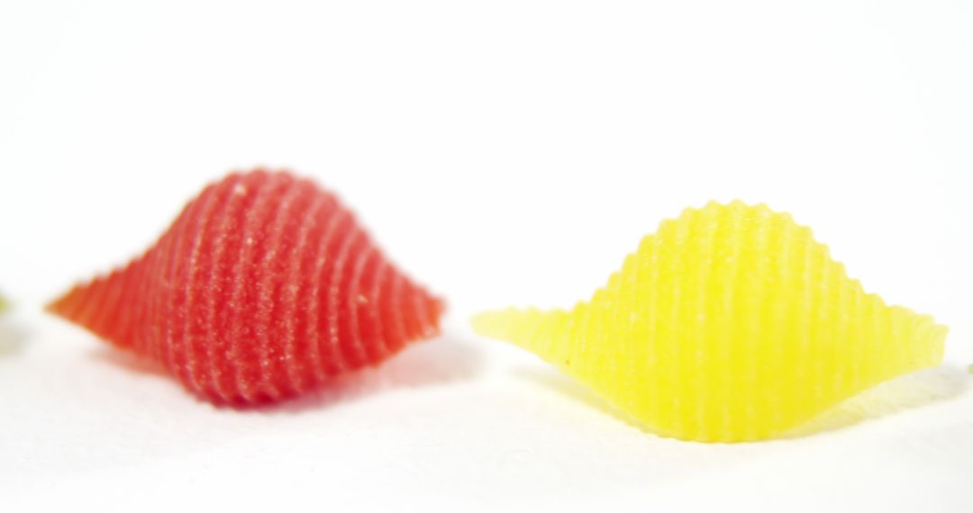 Close-Up of Red and Yellow Pasta Shells on White Background - Free Images, Stock Photos and Pictures on Pikwizard.com