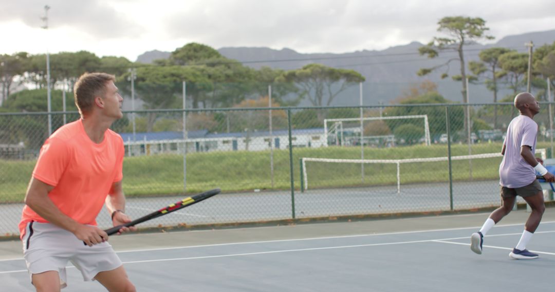 Friends Playing Tennis on Outdoor Court Amidst Scenic Mountain View - Free Images, Stock Photos and Pictures on Pikwizard.com