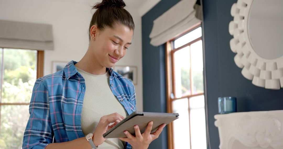 Smiling Teenager Browsing Tablet by Bright Window at Home