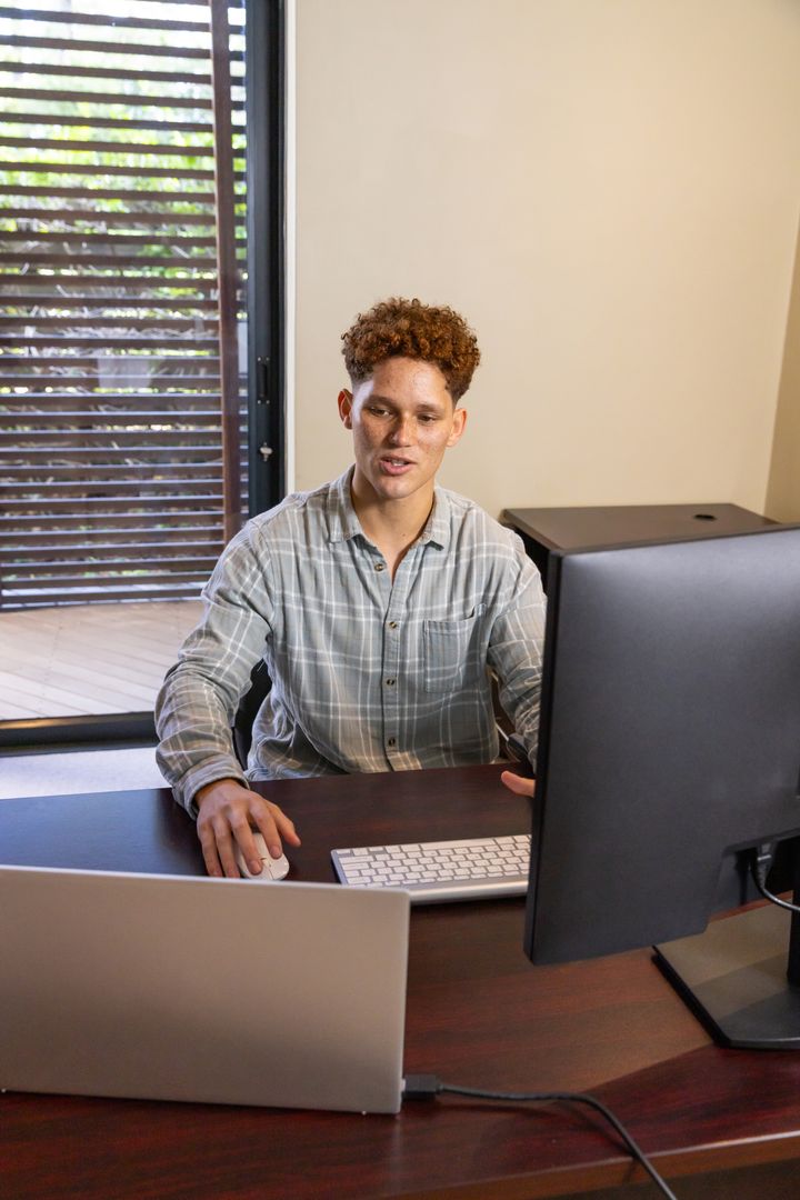 Man Working on Dual Monitors in Home Office Setting