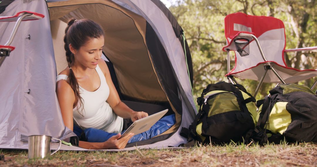 Young Woman Using Digital Tablet Inside Tent While Camping Outdoors - Free Images, Stock Photos and Pictures on Pikwizard.com