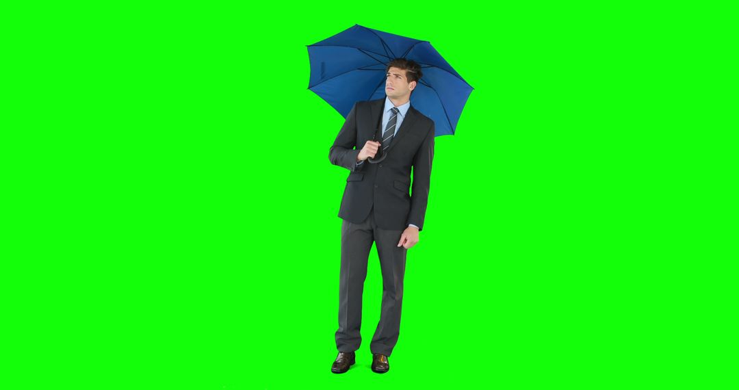 Young businessman sheltering with umbrella on green screen - Free Images, Stock Photos and Pictures on Pikwizard.com