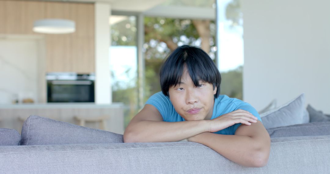 Young Asian Male Relaxing on Sofa in Contemporary Living Room