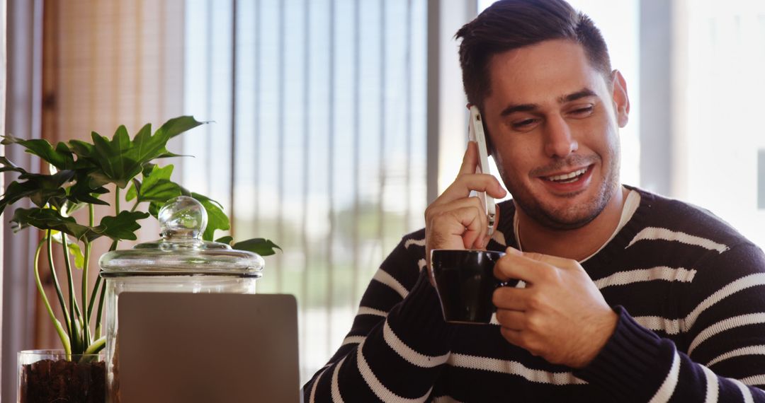 Smiling man enjoying coffee and chatting on phone indoors - Free Images, Stock Photos and Pictures on Pikwizard.com