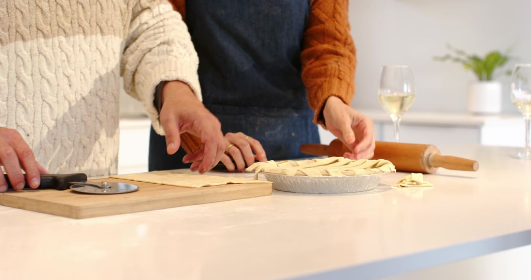 Couple Preparing Lattice Pie Together on White Counter With Rolling Pin and Wine Glasses