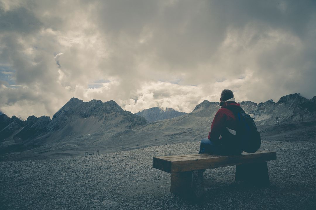 Solitary Traveler Sitting on Bench in Majestic Mountain Landscape - Free Images, Stock Photos and Pictures on Pikwizard.com