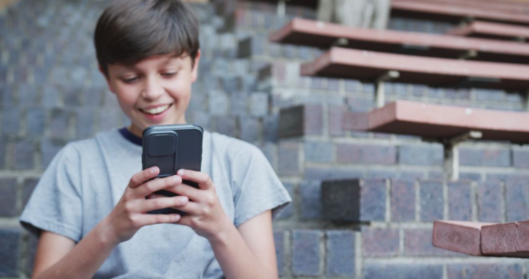 Joyful Boy Using Smartphone on School Steps during Break Time
