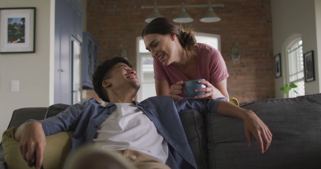 Happy Interracial Couple Relaxing on Sofa with Coffee at Home