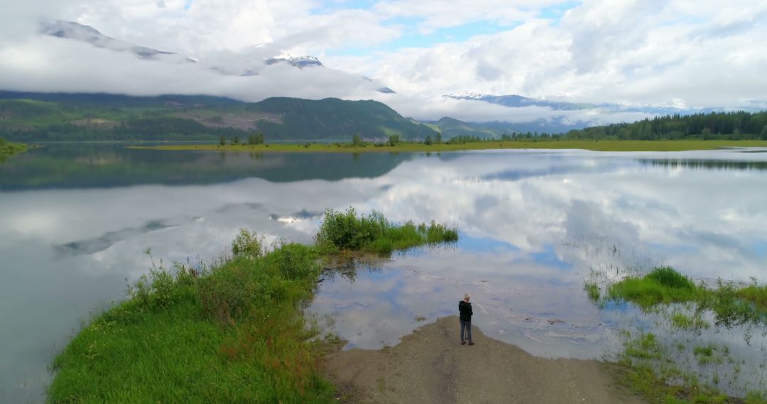 Solitary Figure Admiring Serene Mountain Lake Scenery on Cloudy Day - Free Images, Stock Photos and Pictures on Pikwizard.com