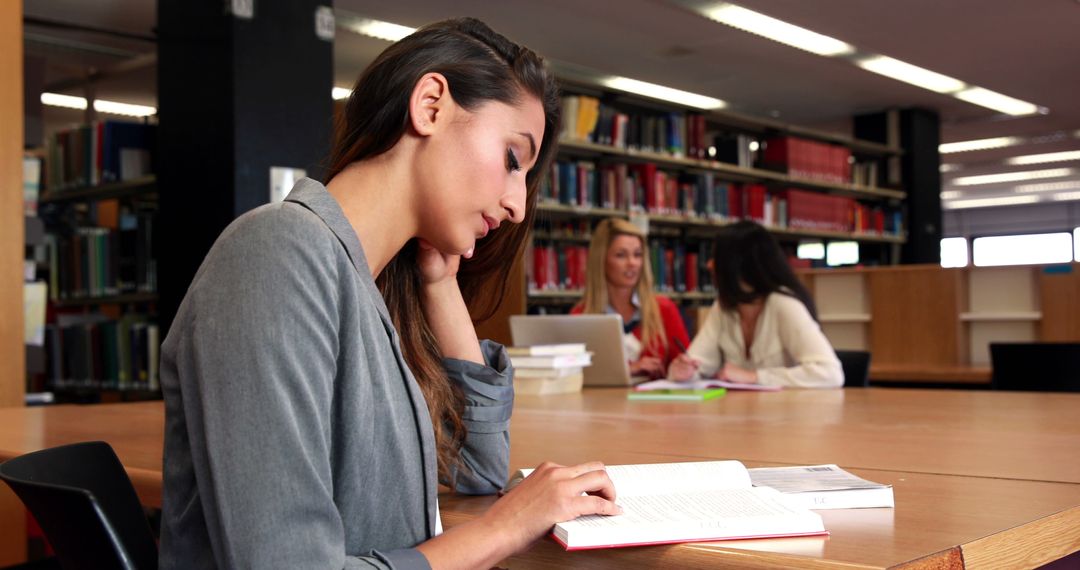 Woman Reading Book in Library While Others Study in the Background - Free Images, Stock Photos and Pictures on Pikwizard.com