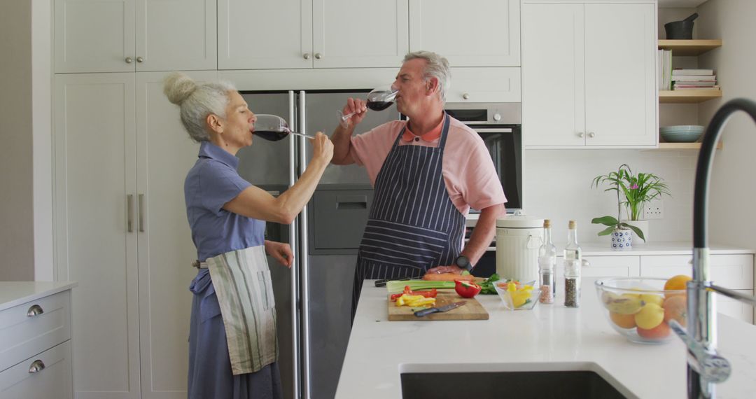 Caucasian senior couple wearing aprons cooking and drinking wine - Free Images, Stock Photos and Pictures on Pikwizard.com