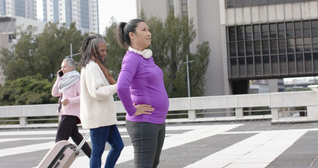 Diverse women walking urban plaza, confident woman with headphones and hands on hips