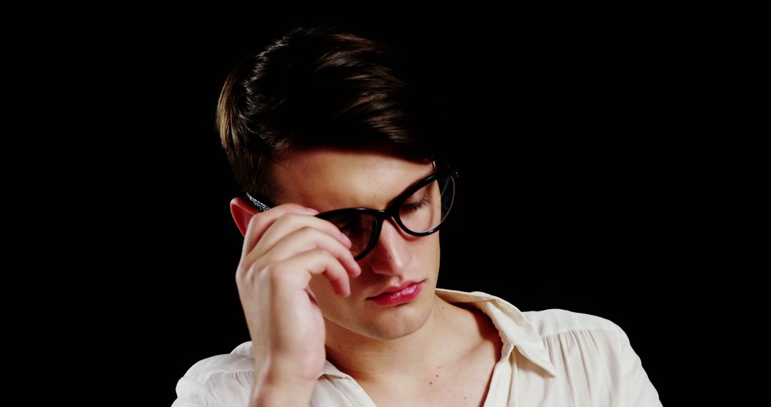 Pensive Young Man Adjusting Glasses Against Black Background - Free Images, Stock Photos and Pictures on Pikwizard.com