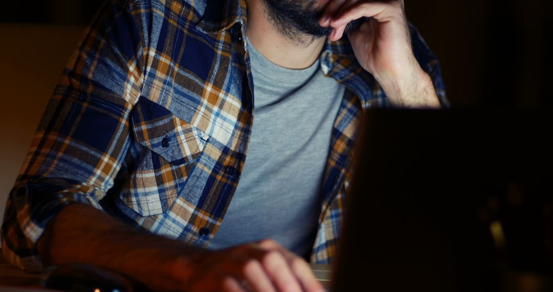 Man Working Late at Night on Computer in Plaid Shirt