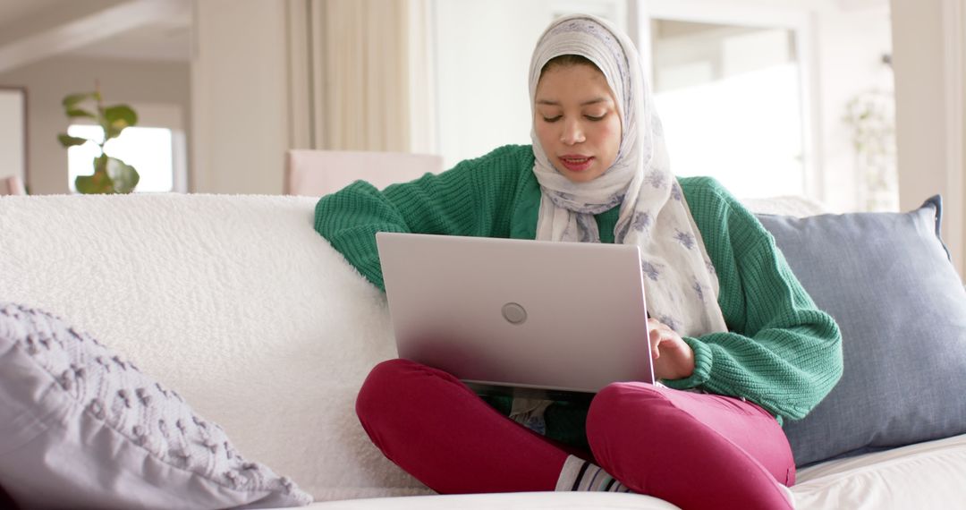 Young Muslim Woman Studying with Laptop on Couch at Home - Free Images, Stock Photos and Pictures on Pikwizard.com