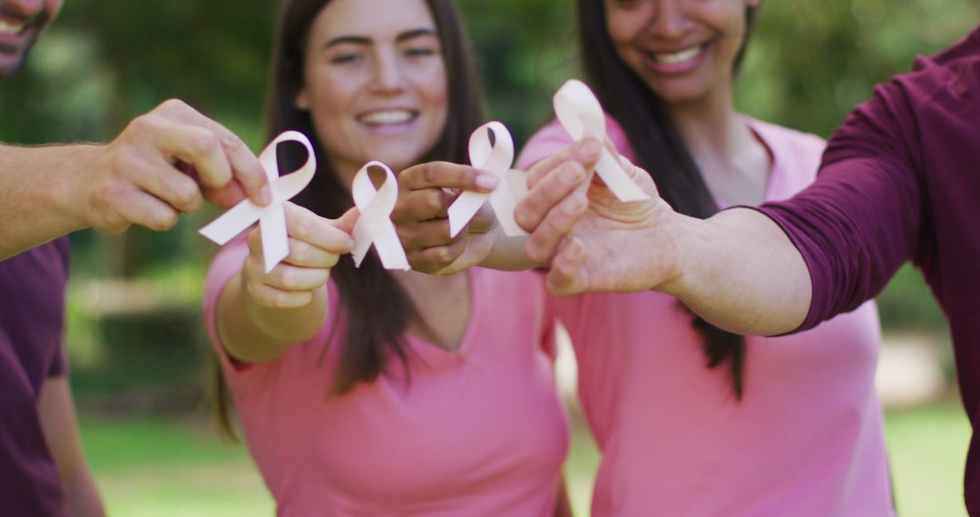 Portrait of diverse group of men and women smiling and holding breast cancer ribbons in park - Free Images, Stock Photos and Pictures on Pikwizard.com