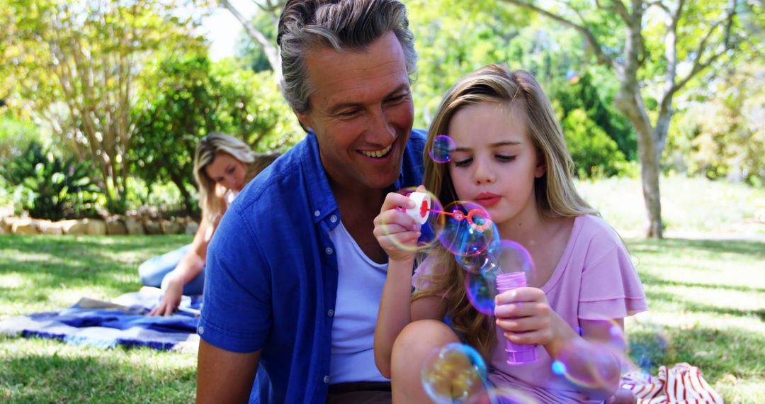 Father and Daughter Blowing Bubbles in Park on Sunny Day - Free Images, Stock Photos and Pictures on Pikwizard.com