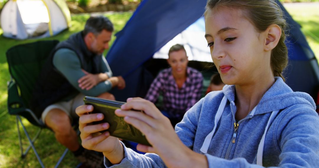 Teen Girl Enjoying Tablet in Nature, Camping with Family - Free Images, Stock Photos and Pictures on Pikwizard.com