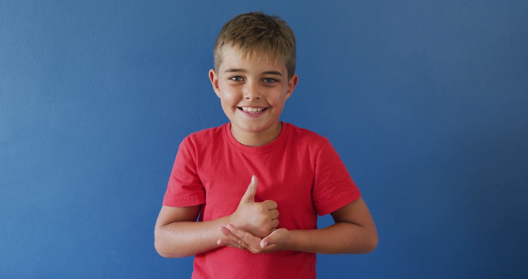 Smiling Young Boy Giving Thumbs Up against Blue Background - Free Images, Stock Photos and Pictures on Pikwizard.com