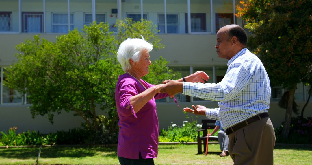 Interracial Elderly Couple Dancing in Garden