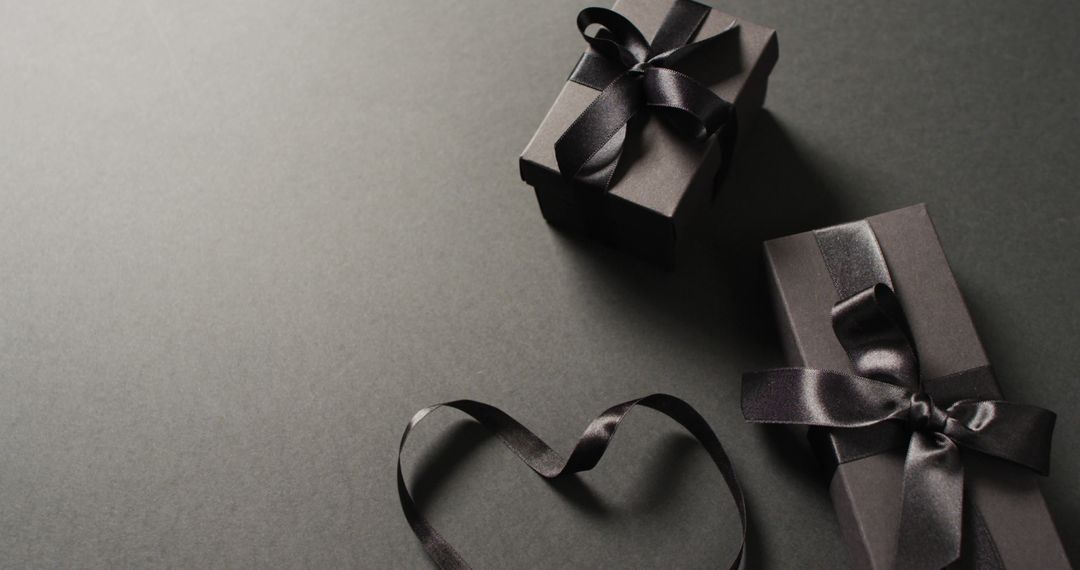 Two black gift boxes with black ribbons and ribbon in heart shape, on dark grey with copy space - Free Images, Stock Photos and Pictures on Pikwizard.com