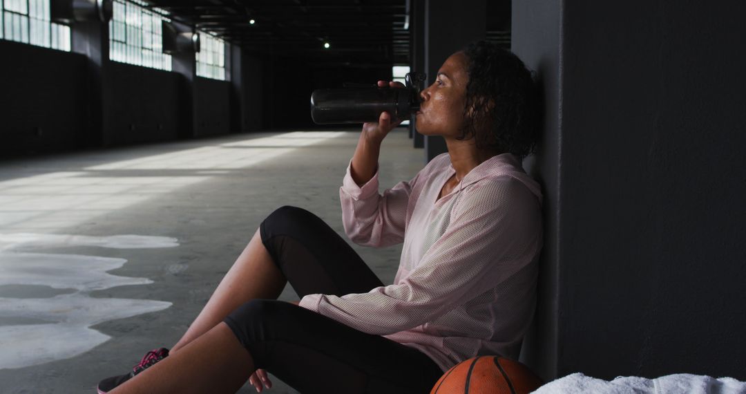 Female Athlete Taking Break and Hydrating during Indoor Basketball Practice - Free Images, Stock Photos and Pictures on Pikwizard.com