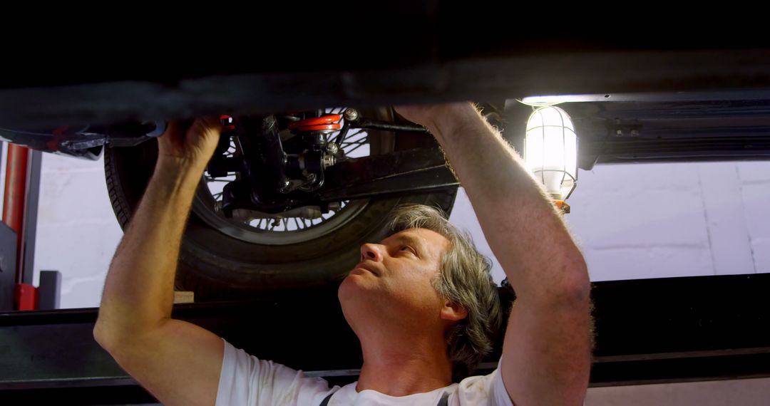 Mechanic Repairing Car Underneath in Auto Shop - Free Images, Stock Photos and Pictures on Pikwizard.com