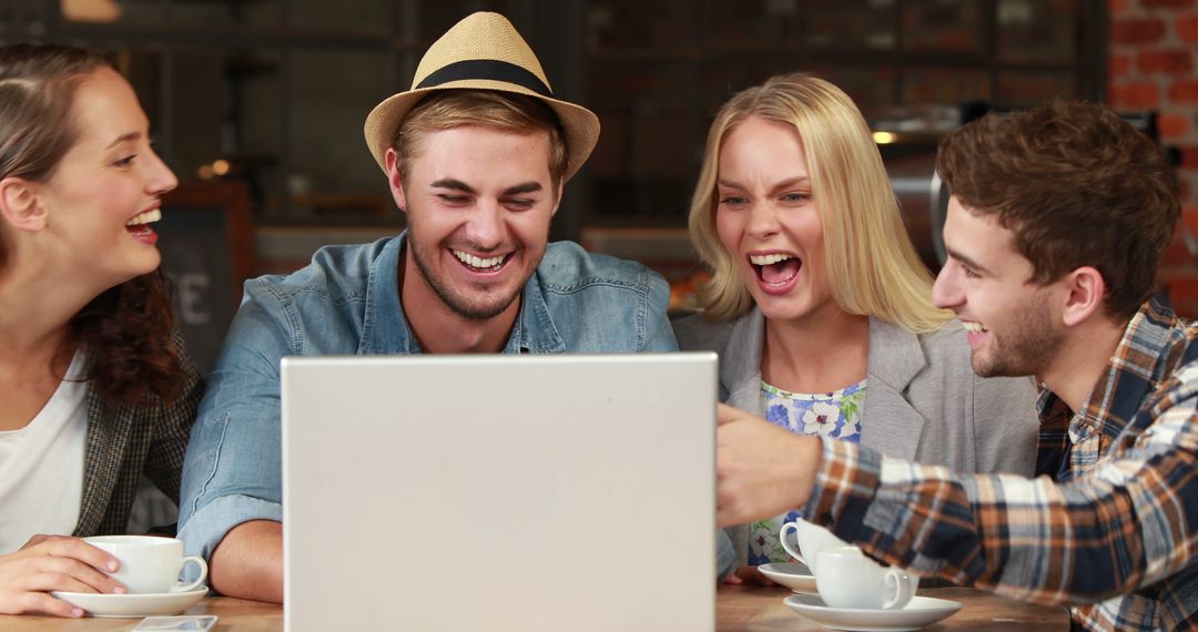 Young Adults Laughing Around Laptop in Café Gathering