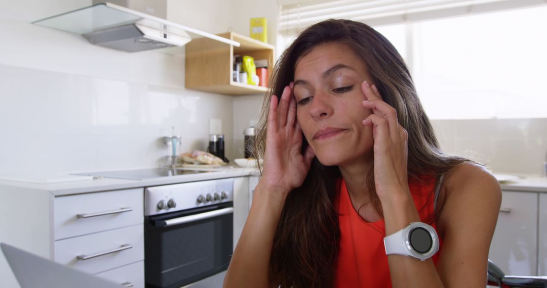 Stressed Woman in Kitchen Rubbing Temples While Working on Laptop - Free Images, Stock Photos and Pictures on Pikwizard.com