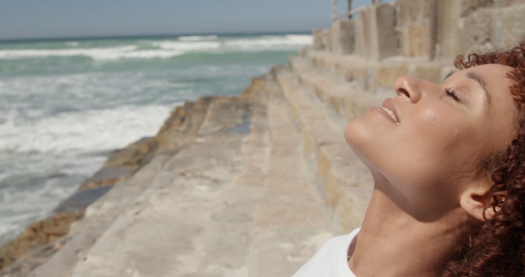 Woman savoring sunshine by oceanfront - Free Images, Stock Photos and Pictures on Pikwizard.com