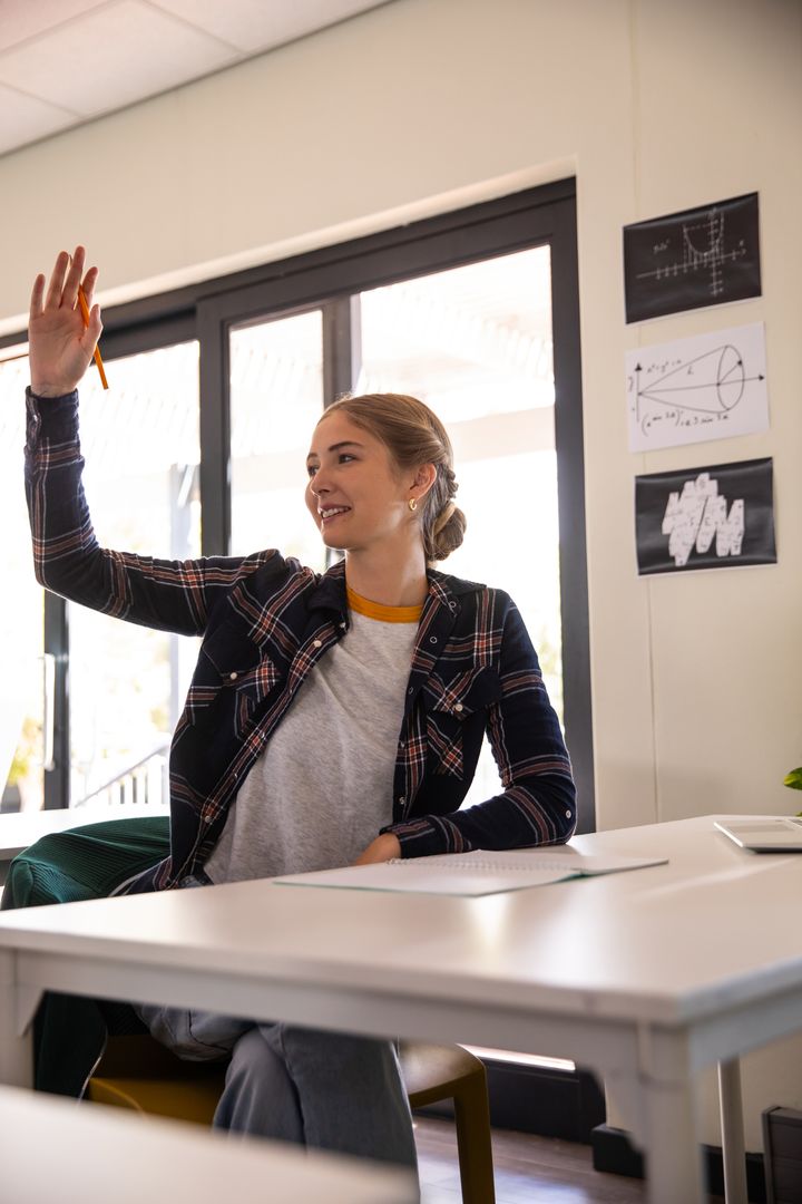 Student Raising Hand with Pencil in Modern Classroom Engaging with Teacher