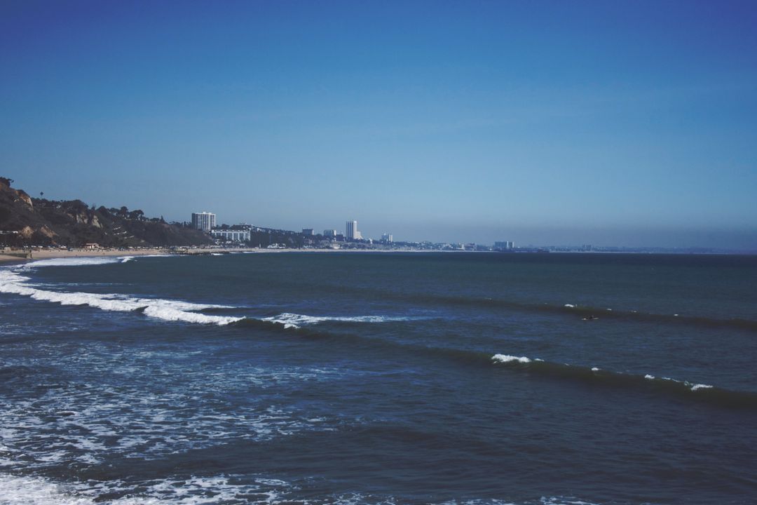 Scenic Coastal View with Waves and Distant City Skyline - Free Images, Stock Photos and Pictures on Pikwizard.com