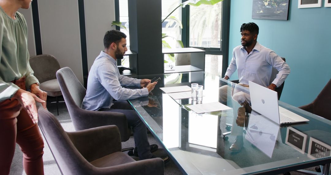 Corporate Team Meeting around Glass Table with Laptops and Documents