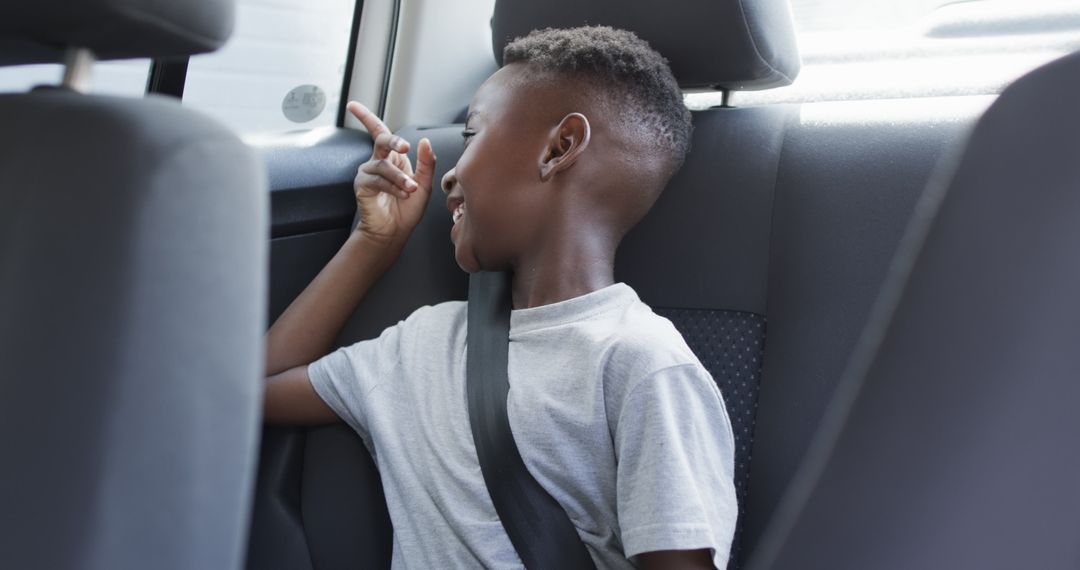 Joyful Boy Gesturing and Smiling in Car Backseat