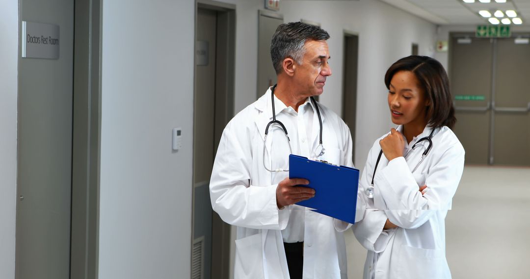 Doctors Reviewing Patient Charts in Hospital Corridor - Free Images, Stock Photos and Pictures on Pikwizard.com