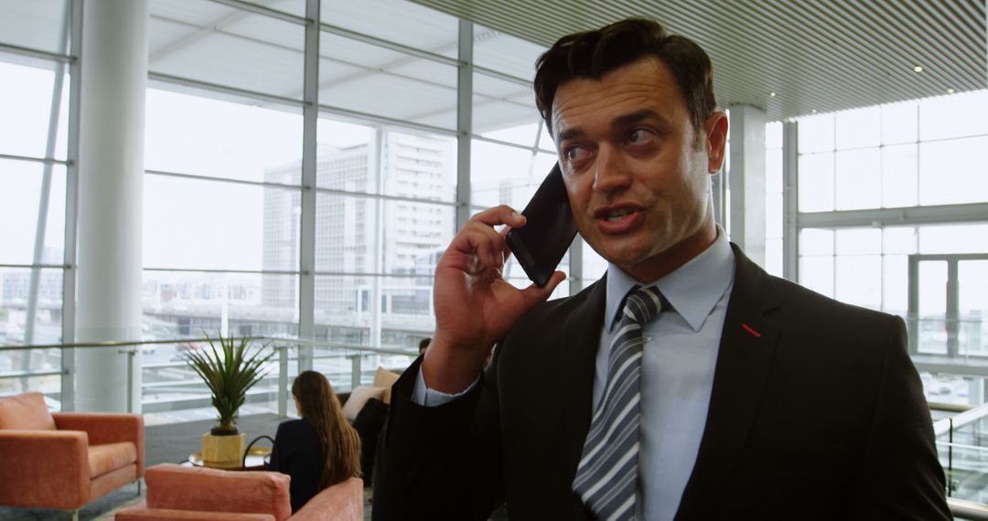 Businessman Talking on Phone in Modern Office Lobby - Free Images, Stock Photos and Pictures on Pikwizard.com