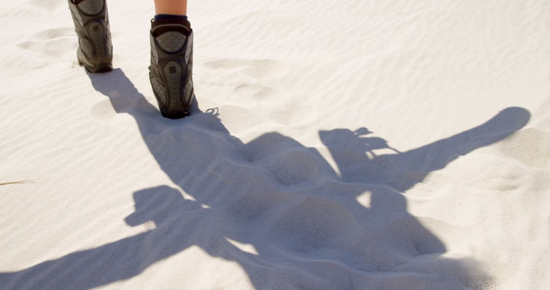 Person walks on sandy terrain, casting a long shadow - Free Images, Stock Photos and Pictures on Pikwizard.com