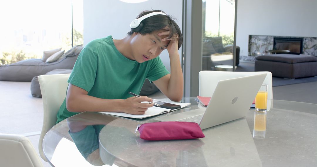 Focused Student Using Tablet for Writing While Listening to Audio