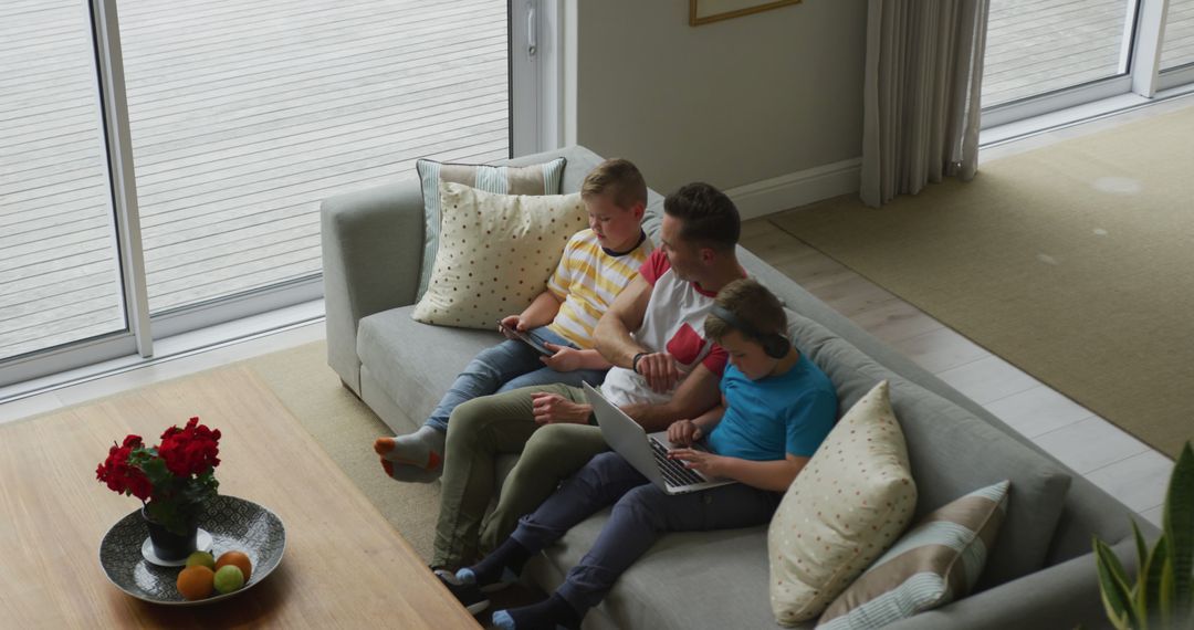 Father and Sons Relaxing in Modern Living Room with Gadgets - Free Images, Stock Photos and Pictures on Pikwizard.com