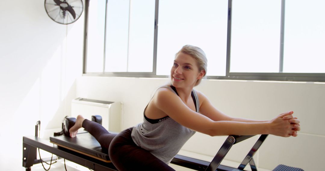 Young Woman Practicing Reformer Pilates in Well-lit Studio - Free Images, Stock Photos and Pictures on Pikwizard.com