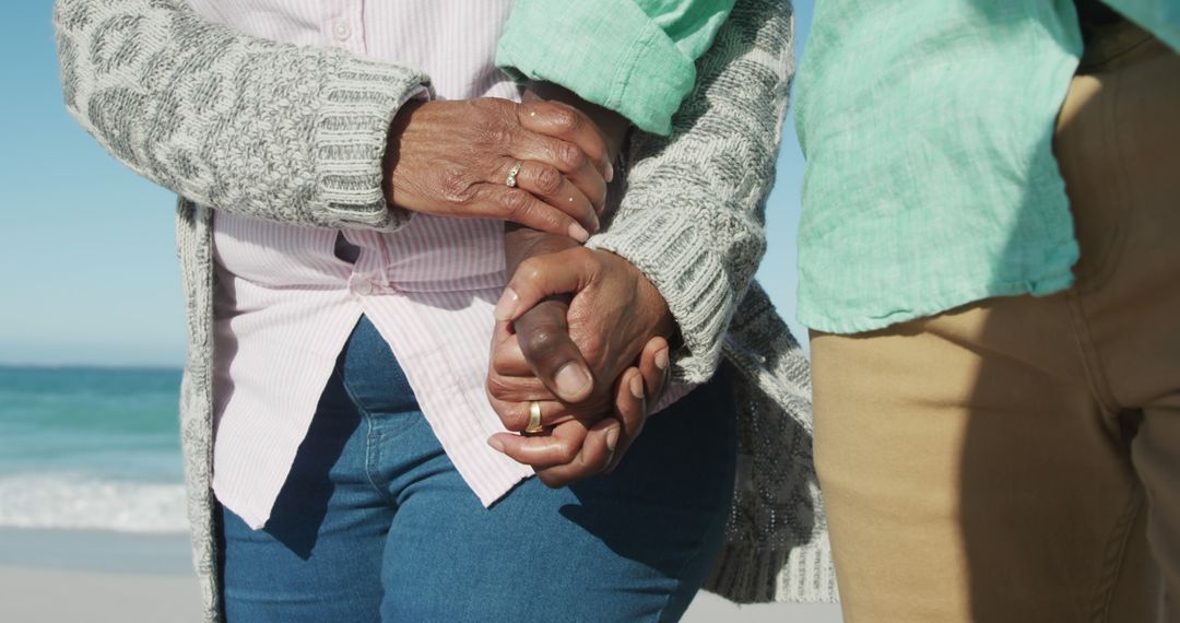 Mid section of african american senior couple holding hands on beach by seaside with copy space - Free Images, Stock Photos and Pictures on Pikwizard.com