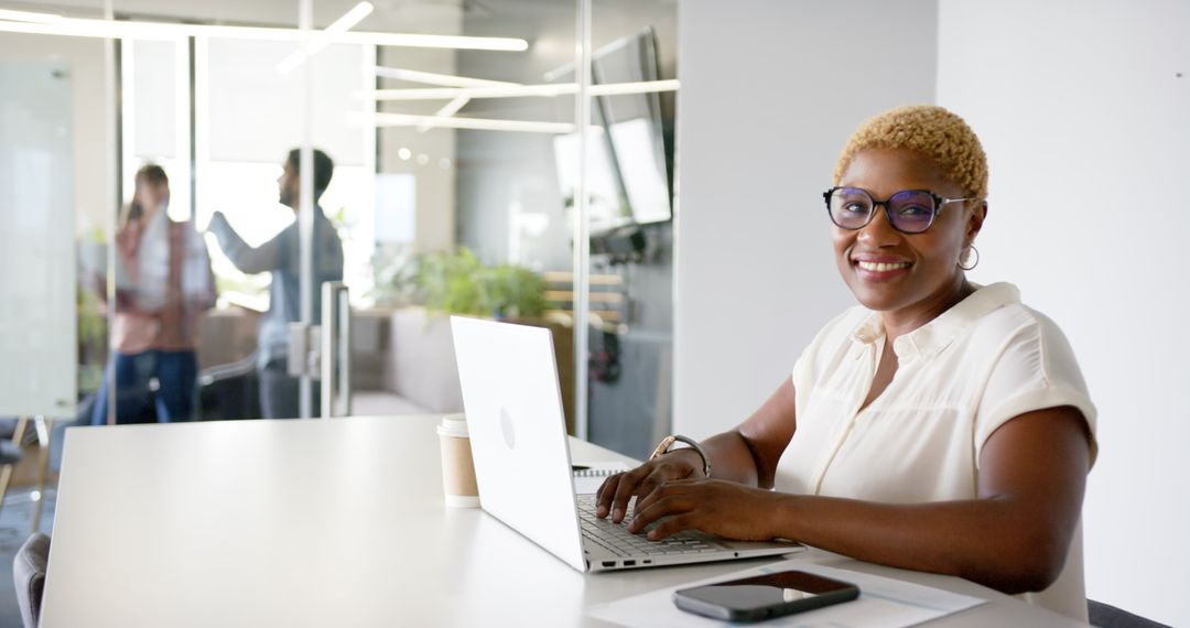 Confident Professional Woman Smiling While Working on Laptop in Modern Office
