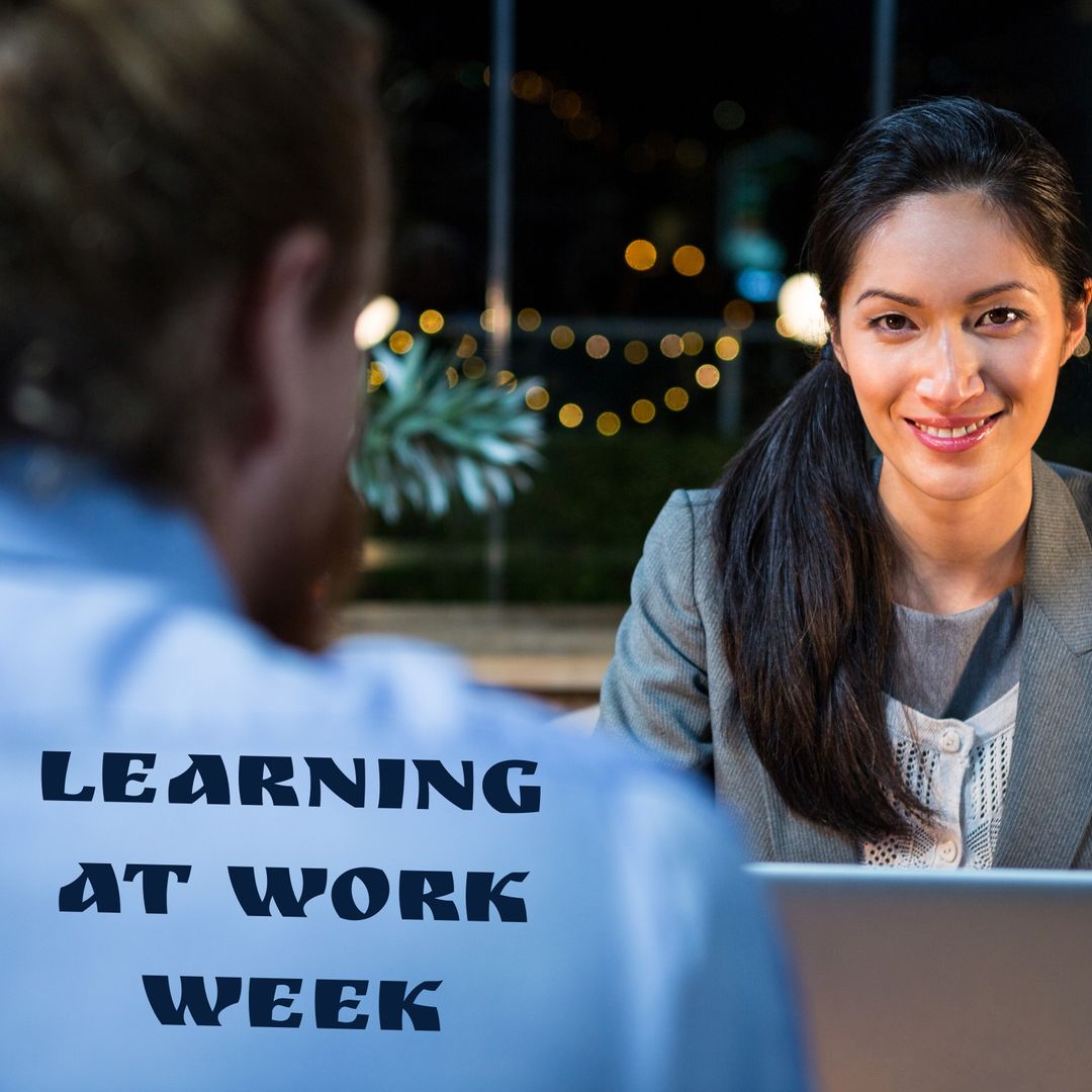 Smiling biracial young businesswoman with colleague by learning at work ...