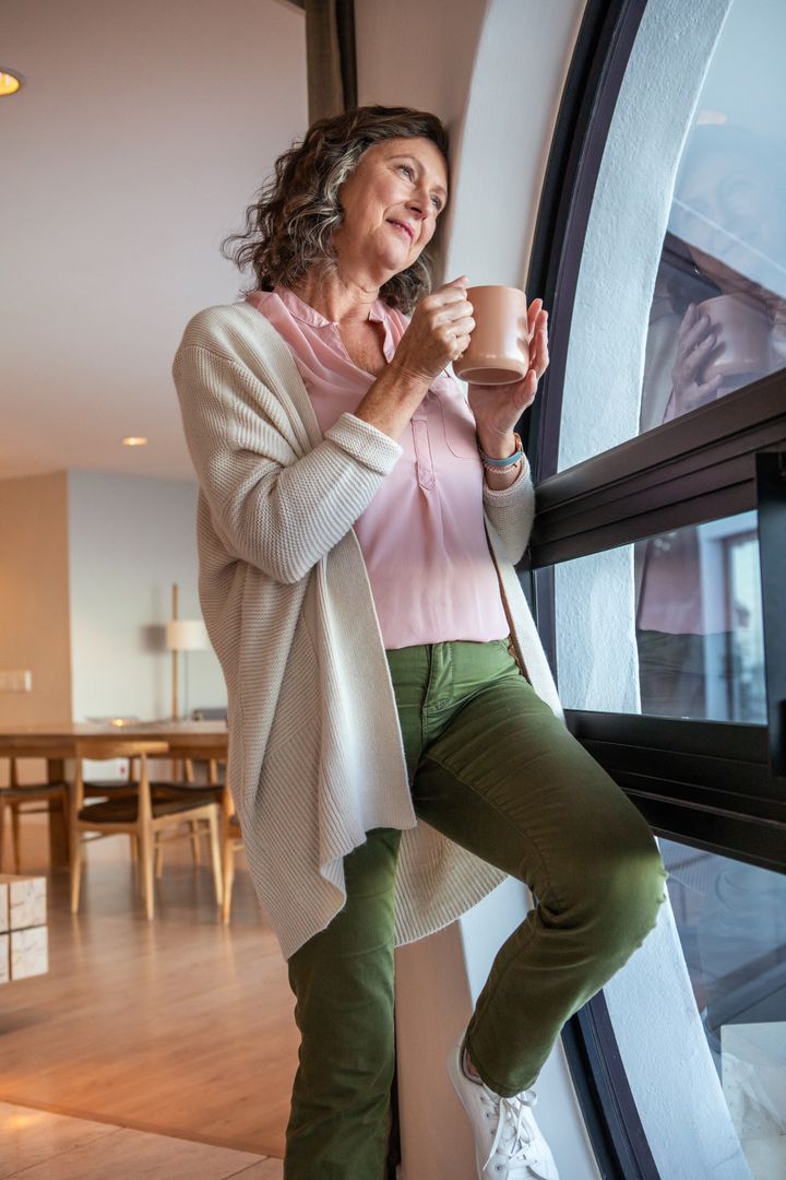 Senior Woman Relaxing with Warm Drink By Arched Window